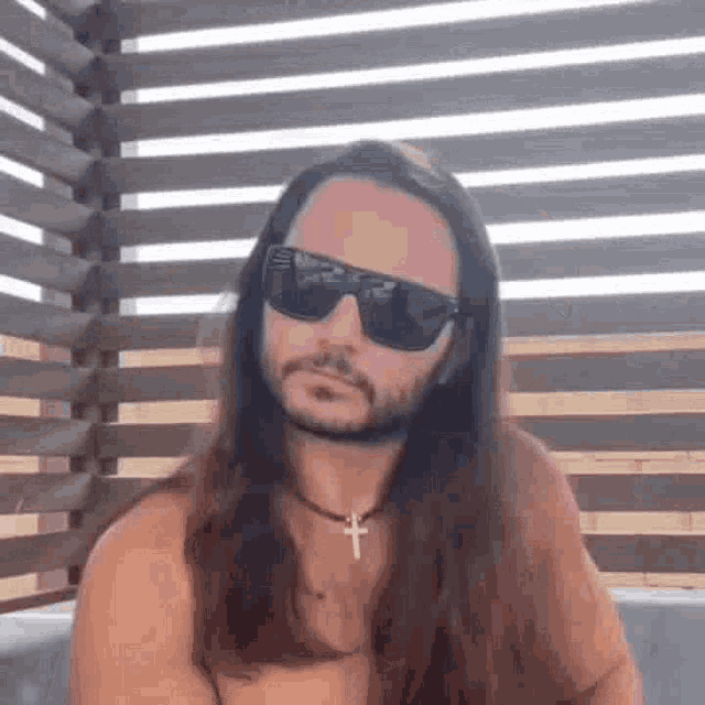 a shirtless man with long hair and a beard wearing sunglasses .