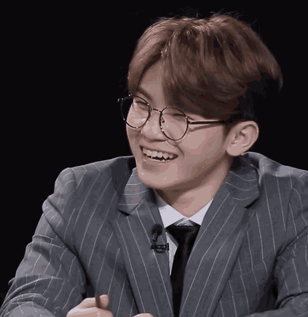 a man wearing glasses and a suit has a microphone attached to his jacket