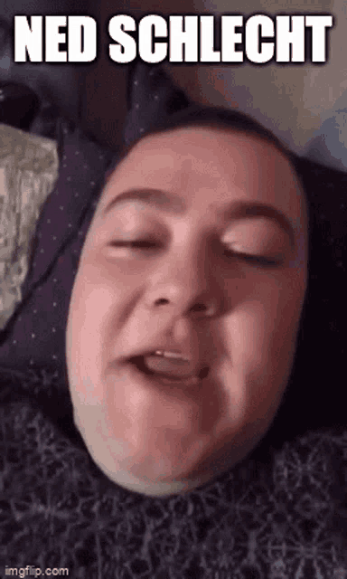 a man is laying in bed with his eyes closed and making a funny face with the words ned schlech written above him .