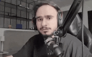 a man wearing headphones and a microphone is sitting in front of a computer .