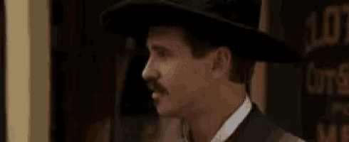 a man with a mustache and hat is smiling .