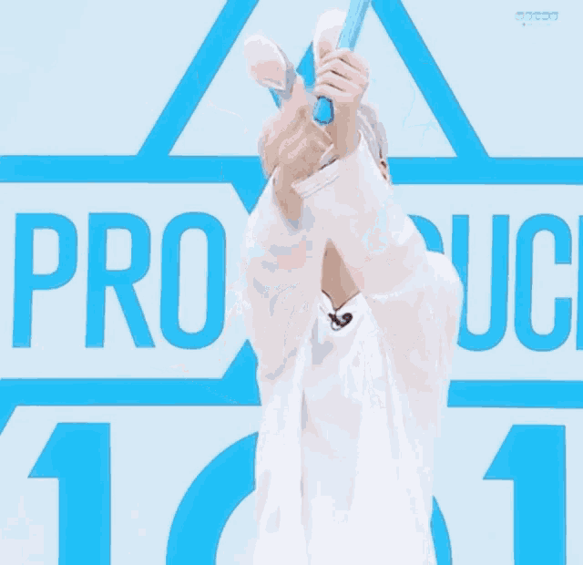 a boy wearing bunny ears giving a thumbs up in front of a sign that says produce 101