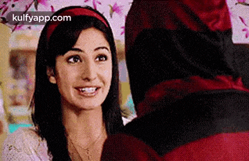 a woman is smiling while looking at a man in a red hat .