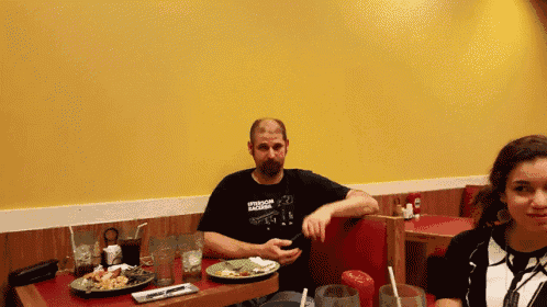 a man wearing a t-shirt that says freedom fighters sits at a table