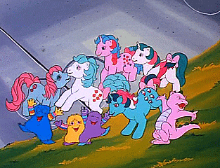 a group of ponies are standing on top of a grassy hillside