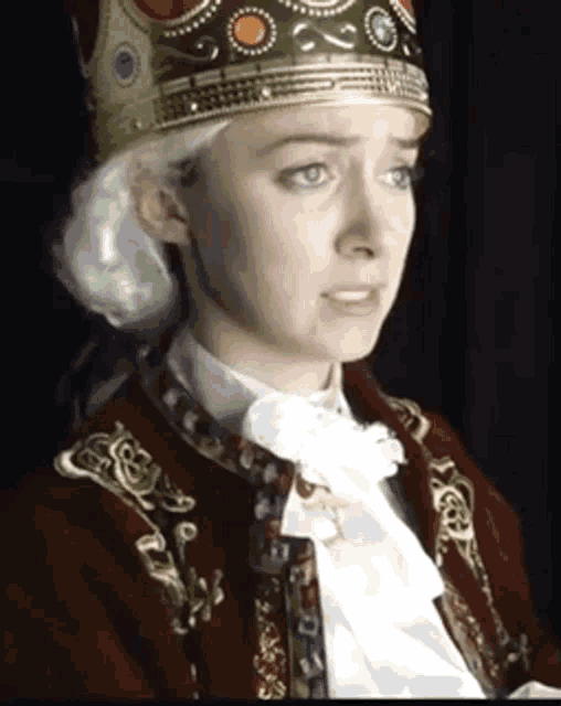 a woman with a crown on her head is wearing a red jacket