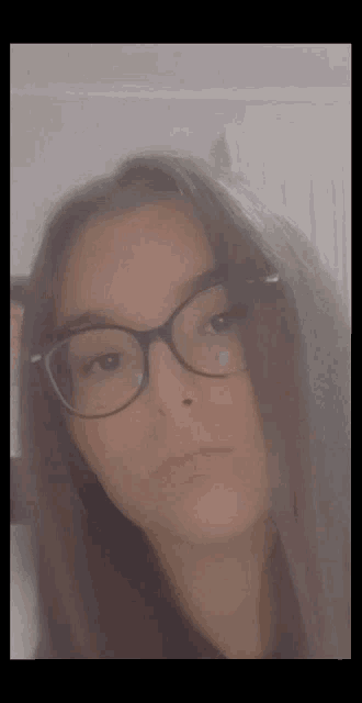 a girl with long hair and glasses is taking a selfie