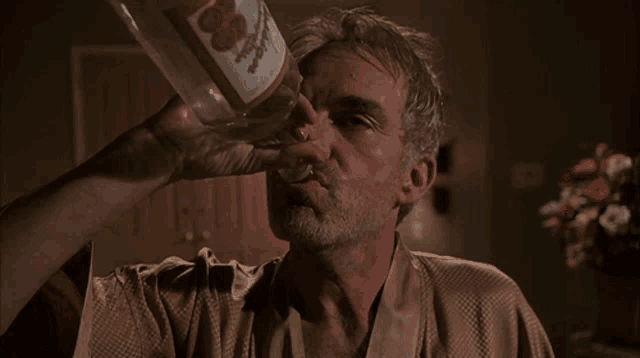 a man is drinking from a bottle that says ' 100 ' on it