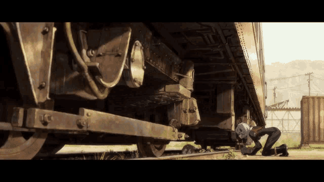 a man is kneeling down next to a train that has the letter u on it