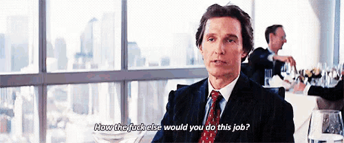 a man in a suit and tie is sitting at a table talking to another man .