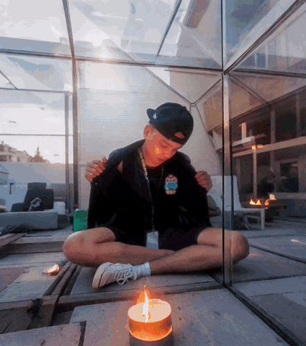 a man sits on the ground with a candle in front of him