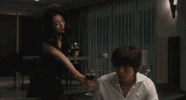 a woman in a black dress holds a glass of wine next to a man in a white shirt