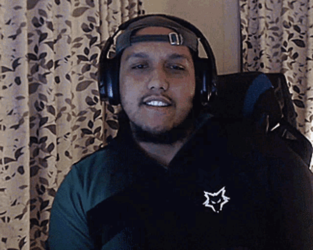 a man wearing headphones and a hat has a white star on his shirt