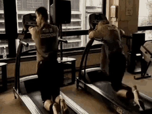 two men are riding treadmills in a gym .