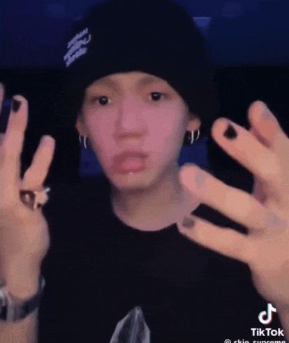 a young man wearing a black beanie and black nail polish is making a funny face .