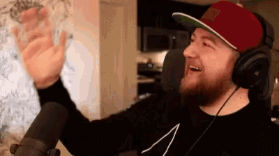 a man wearing headphones and a red hat is smiling and waving