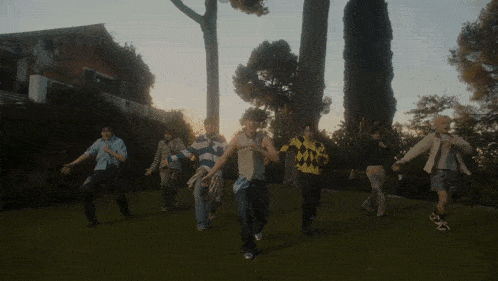a group of young men are dancing in a grassy field