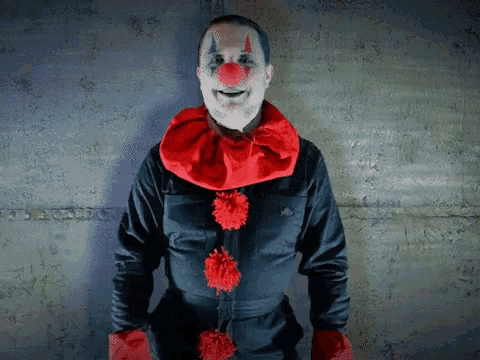 a man dressed as a clown with red pom poms