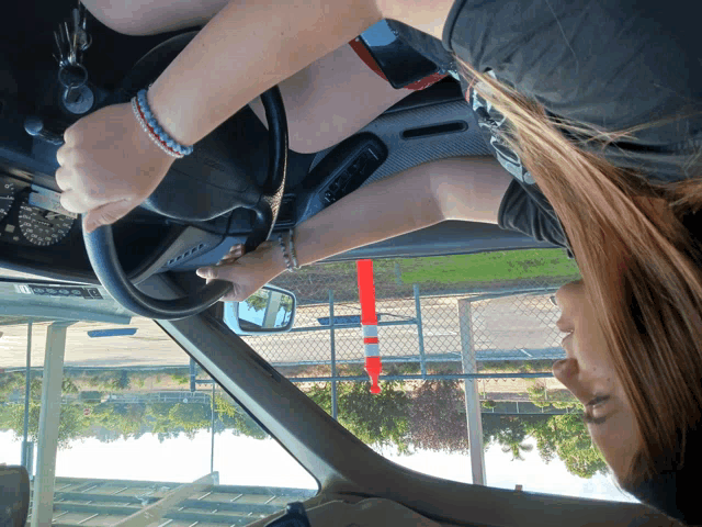 a woman is driving a car with the steering wheel turned upside down