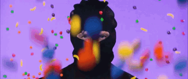 a person in a balaclava is surrounded by colorful candies .