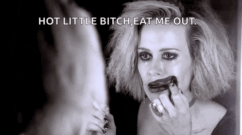 a black and white photo of a woman applying makeup with the words hot little bitch eat me out