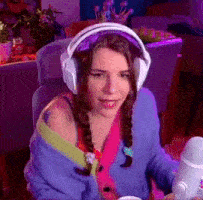 a woman wearing headphones and a colorful sweater is holding a microphone .