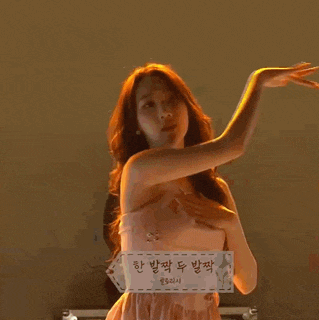a woman in a pink dress is dancing in a dark room .