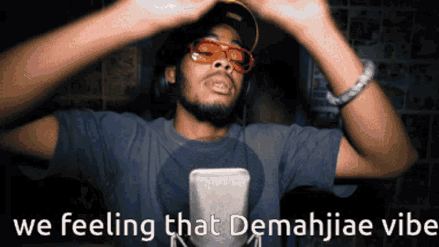 a man wearing sunglasses and headphones says " we feeling that demahjiae vibe "