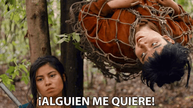 a man is hanging upside down in a rope cage with the words alguien me quiere below him