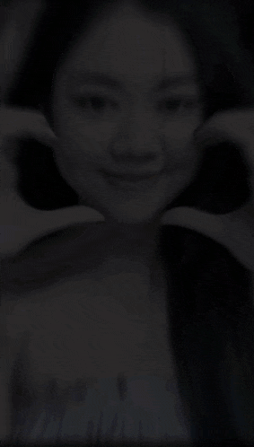 a woman making a heart shape with her hands on her face