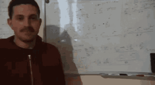 a man stands in front of a white board with math problems on it