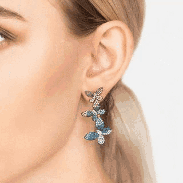 a close up of a woman 's ear with a pair of colorful butterfly earrings