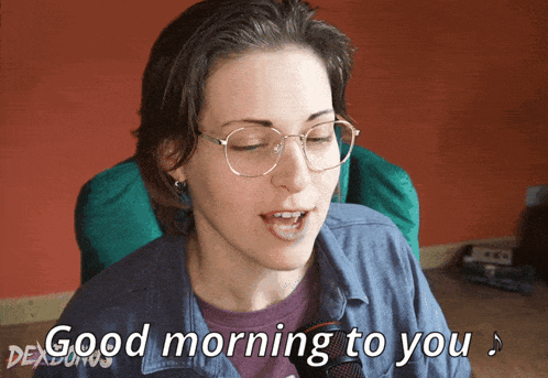 a woman wearing glasses and a purple shirt says good morning to you