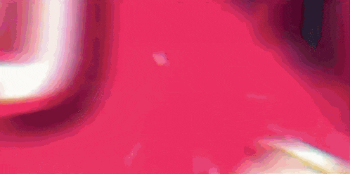 a girl with pink hair is holding a gun in front of a pink background with japanese writing .