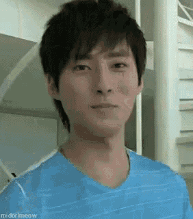 a young man in a blue shirt is standing in front of a staircase .