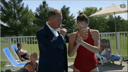 a woman in a red swimsuit is standing next to a man in a suit