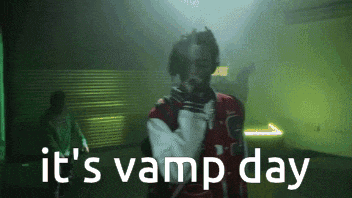 a man in a varsity jacket is standing in a dark room with the words it 's vamp day below him