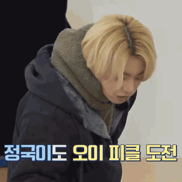 a man with blonde hair is wearing a scarf around his neck and a jacket