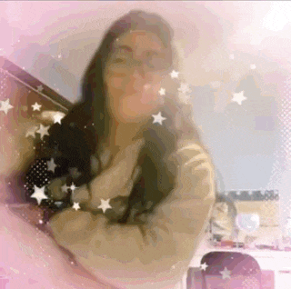 a woman is standing in front of a pink background with stars and sparkles .