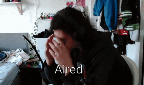a person wearing headphones covering their face with their hands and the word aired written above them