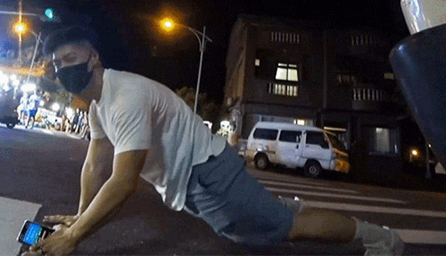 a man wearing a mask is laying on the ground using his phone