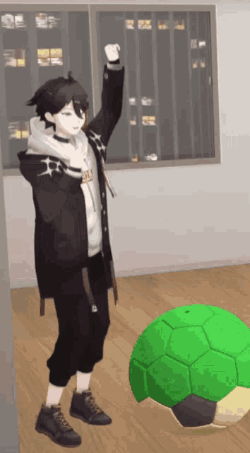 a boy in a black jacket stands next to a green ball