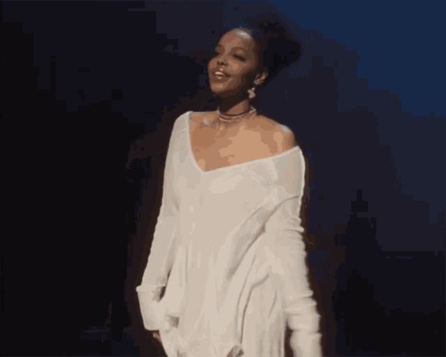 a woman wearing a white sweater and a choker stands on a stage