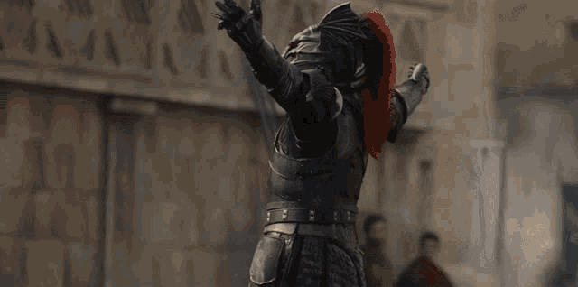 a man in a knight 's armor has his arms outstretched in the air