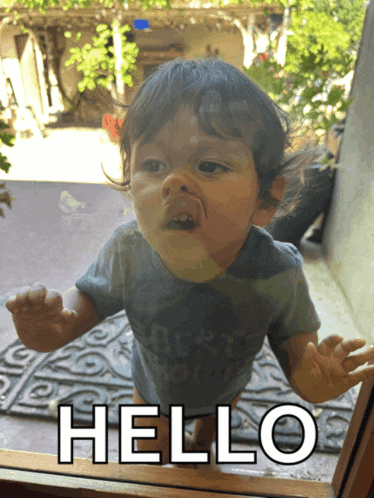 a baby is looking out a window with the words hello written on the glass