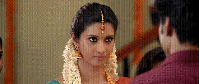 a woman with flowers in her hair looks at the camera