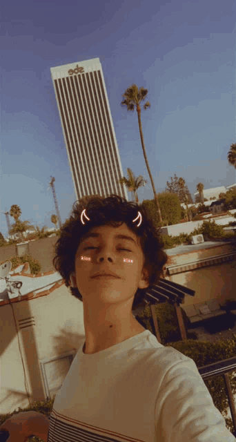 a young boy taking a selfie with a building in the background that says king