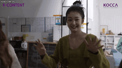 a woman in a green sweater is smiling in front of a k-content logo