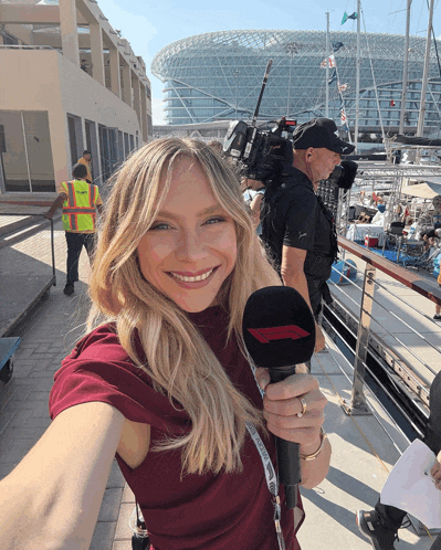 a woman holding a microphone that says ' formula one ' on it