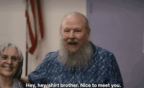 a man with a beard is talking to a woman with the words hey hey shirt brother nice to meet you